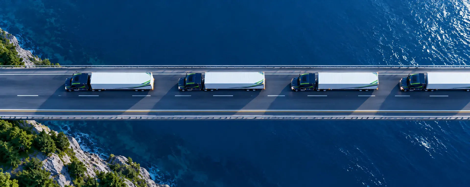 A line of tractor-trailers crossing a bridge over the sea